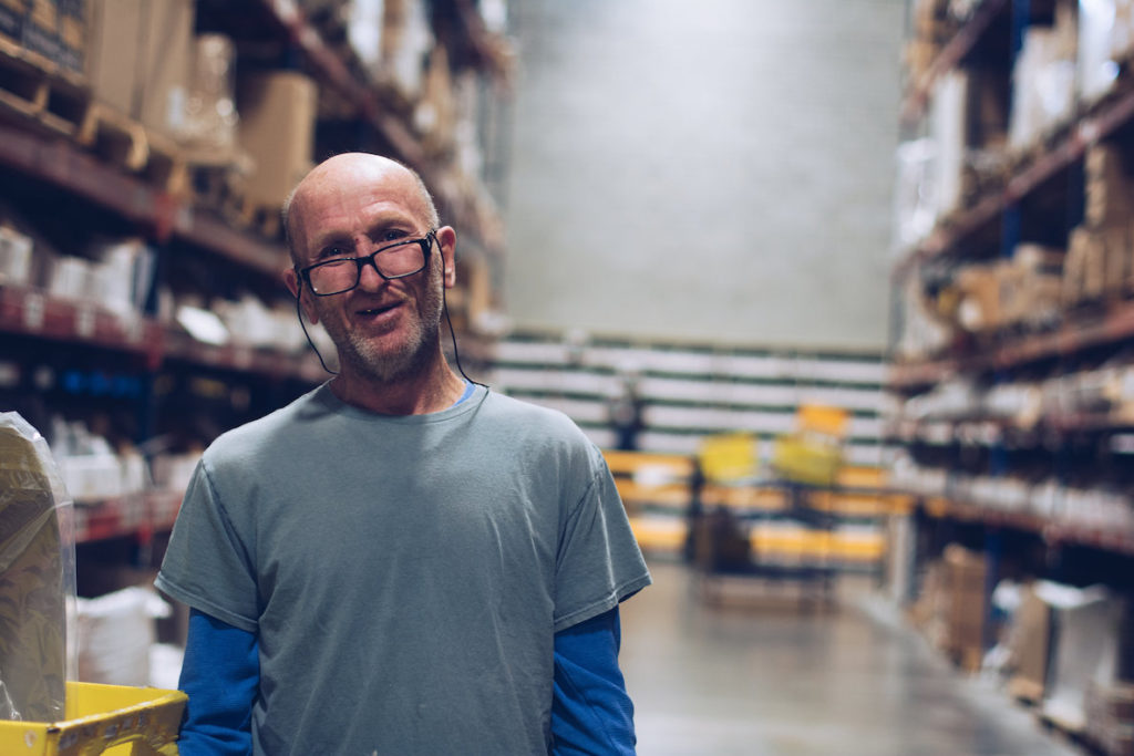 A man—an employee of First Step Staffing—stands in the factory where he works.