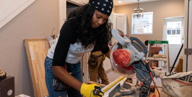 Monica Miraglilo, developer with Aequo and founder of Girlbuild, measuring and cutting woood with a saw